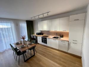 uma cozinha com uma mesa e uma cozinha com armários brancos em Apartmán Thermal Park 