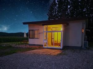 a small house with a large glass door at night at fukiconoie in Tokachi