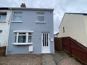 a blue house with a fence in front of it at Ravenhill Townhouse Belfast in Belfast