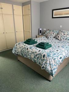 a bedroom with a bed with green towels on it at The Coach House at Copper Hall in Leominster