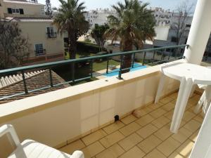 a balcony with a view of a pool and palm trees at Apartamento com Piscina junto a Praia - Alvor in Alvor