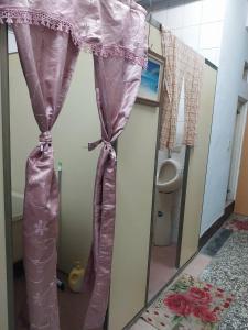 a pink shower curtain in a bathroom with a toilet at 三角窗民宿 