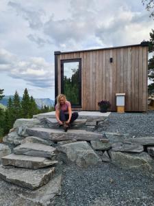 una mujer sentada en unas rocas delante de un edificio en Vidsyn Midjås en Vistad