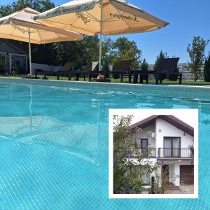 een zwembad met een parasol en een huis bij Modern 3 bedroom house with a private pool in Popeşti-Leordeni
