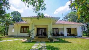 Ridigama的住宿－Raddegoda Walawwa Kurunegala，一座带草地庭院的白色小房子