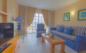 a living room with a blue couch and a tv at El Marques Palace by Intercorp Group in Puerto de Santiago