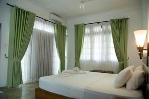 Ridigama的住宿－Raddegoda Walawwa Kurunegala，一间卧室配有一张带绿色窗帘的大床