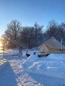 a tent and a bench in the snow at Glamping 4 saisons @ Eco Lodge Bûcheron Bergère in Ormstown