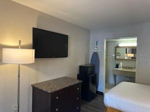 a hotel room with a bed and a television on the wall at Days Inn by Wyndham WestEnd Alexandria,VA Washington DC Area in Alexandria
