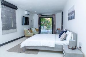 a white bedroom with a large bed and a window at Upendo Boutique Hotel, Dar es Salaam in Dar es Salaam