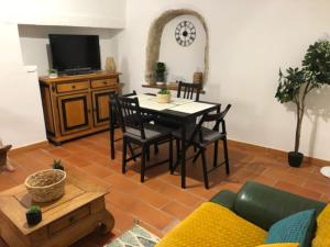 un soggiorno con tavolo, sedie e TV di Maison coeur de village Saint-Jean-de-Fos a Saint-Jean-de-Fos