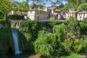 una cascata di fronte a un villaggio con case di Maison coeur de village Saint-Jean-de-Fos a Saint-Jean-de-Fos