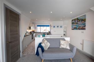a living room with a chair and a kitchen at Saltwhistle View- Beachside Luxury, Stunning Views in Teignmouth