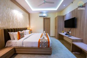 a hotel room with a bed and a flat screen tv at Hotel Golden Petals in Varanasi