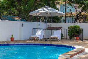 a swimming pool with two chairs and an umbrella at Upendo Boutique Hotel, Dar es Salaam in Dar es Salaam