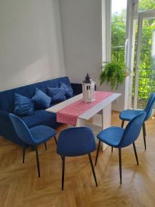 uma sala de estar com um sofá azul e uma mesa e cadeiras em Urban Nest Apartments Brodowicza 14 em Cracóvia