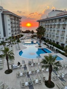 a resort with a pool and chairs and a sunset at Lander Luxury Apartment, 5 Star Hotel, Kusadasi in Kuşadası