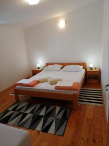 ein Schlafzimmer mit einem Bett mit zwei Kissen und einem Teppich in der Unterkunft Bruno apartman in Selce