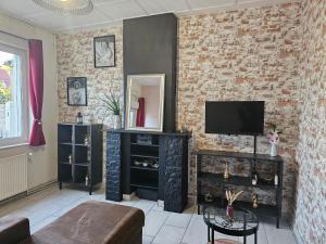 a living room with a tv and a brick wall at Maison familiale, 3 chambres, jardin et parking privé in Montigny-en-Gohelle