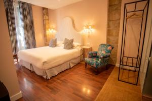 une chambre d'hôtel avec un lit et une chaise dans l'établissement Hotel Carmen Boutique, à Baeza