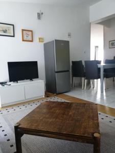 ein Wohnzimmer mit einem Kühlschrank und einem Tisch in der Unterkunft Bruno apartman in Selce