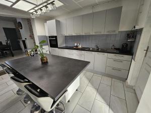 cocina con armarios blancos y encimera negra en Maison familiale, 3 chambres, jardin et parking privé en Montigny-en-Gohelle
