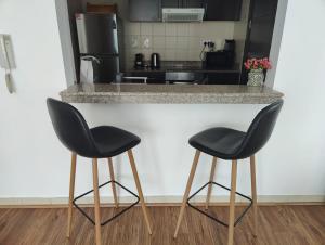 two black chairs sitting at a counter in a kitchen at 1BR apartment, Stunning Dubai Marina view, 5 min walk to JBR beach, 30 sec walk to tram and bus stations in Dubai