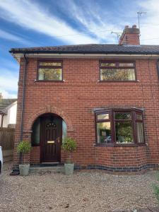 a red brick house with a door and two plants at Self Contained Guest Suite in South Milford