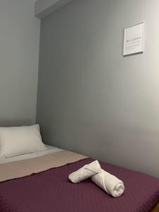 ein Bett mit einem Handtuch auf einer lila Decke in der Unterkunft GP Shelter in Athen