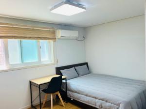 um quarto com uma cama, uma secretária e uma janela em BB Hongdae Line em Seul