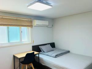 een slaapkamer met een bed, een bureau en een raam bij BB Hongdae Line in Seoul