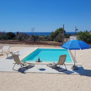 una piscina con sedie, tavolo e ombrellone di Villa Pescoluse a Marina di Pescoluse