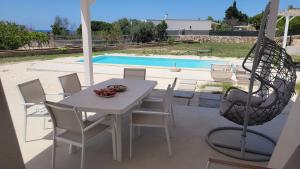 un patio con tavolo, sedie e piscina di Villa Pescoluse a Marina di Pescoluse