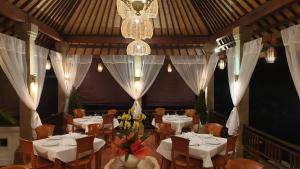 a restaurant with white tables and chairs and a chandelier at The Kanjeng Signature Sidemen in Sidemen