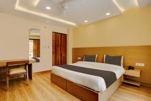 1 dormitorio con 1 cama grande y escritorio en Collection O Hotel Orange Regency, en Dehradun