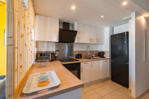 a kitchen with white cabinets and a black refrigerator at Lac-Montagne-Leman-Geneva, Garage, Tram in Annemasse