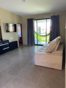 a large living room with a couch and a balcony at CHEZ TUPÃ SUÍTES in Uruau