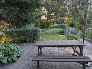 una mesa de picnic de madera y una sombrilla en el jardín en Little Bear Apartment, en Mogyoród