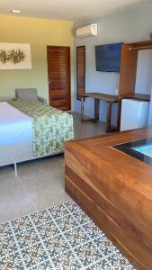 a bedroom with a bed and a desk and a television at CHEZ TUPÃ SUÍTES in Uruau