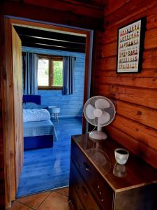 1 dormitorio con 1 cama y un ventilador en la cómoda en Le Chalet de la Dordogne, en Mauzac-et-Grand-Castang