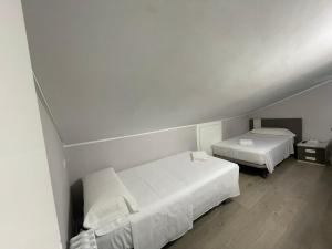 ポンフェラーダにあるLa Rosa Azul Roomsの白い壁とウッドフロアの客室で、ベッド2台が備わります。