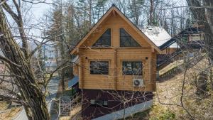 a log cabin in the woods with snow on it at Wadano Gateway Suites & Apartments in Hakuba