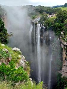 a waterfall on the side of a mountain with clouds at Louis at Magwa Falls in Lusikisiki