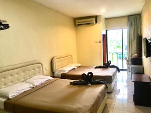 two beds sitting in a room with a window at ANZ LANGKAWI INN in Pantai Cenang