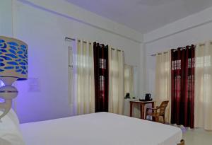 Hotel Surya Inn في Pura Raghunāth: غرفة نوم بسرير وطاولة وكراسي