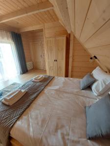 duże łóżko w pokoju z drewnianym sufitem w obiekcie Osada Witów - Domek we wsi w mieście Witów