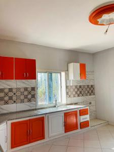 een keuken met rode en witte kasten en een raam bij BEN Wanes 