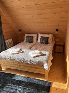 łóżko w drewnianym domku z dwoma ręcznikami w obiekcie Osada Witów - Domek we wsi w mieście Witów