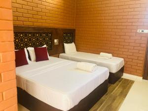 two beds in a room with a brick wall at Monaara Leisure - Anuradhapura in Anuradhapura