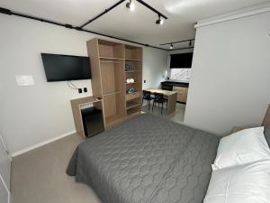 um quarto com uma cama, uma televisão e uma secretária em Studios 422 em Pomerode